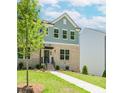 Charming townhome with a brick facade, manicured lawn, and inviting entrance with black door and awning at 1230 Ainsworth Aly # 34, Sugar Hill, GA 30518