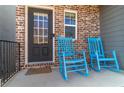 Inviting front porch with brick facade, black door, and blue rocking chairs create a relaxing entry at 360 Winston Cir, Canton, GA 30114