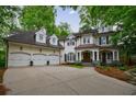 A stately white brick residence featuring a three-car garage, well-manicured landscaping, and a covered front porch at 1412 Lanier Ne Mnr, Atlanta, GA 30319