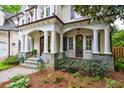 Covered front porch with stone accents, elegant columns, and stylish lighting at 1412 Lanier Ne Mnr, Atlanta, GA 30319
