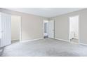 Spacious bedroom with light gray walls, carpet, and three doorways with modern white doors at 4872 Lewis Rd, Powder Springs, GA 30127