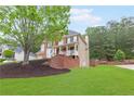 Beautiful brick home with covered porch, lush lawn, and mature trees at 1342 Winborn Nw Cir, Kennesaw, GA 30152
