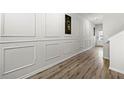 Elegant hallway features wood flooring, decorative wall panels, and stylish artwork leading to a bright doorway at 7492 Knoll Hollow Rd, Lithonia, GA 30058