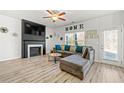 Cozy living room with a fireplace, comfortable seating, a ceiling fan, and abundant natural light at 7492 Knoll Hollow Rd, Lithonia, GA 30058