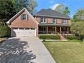 Traditional brick home featuring a covered front porch and well-maintained landscaping at 2040 Parliament Dr, Lawrenceville, GA 30043