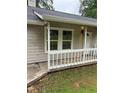 Exterior view of a home with light siding and a white, small porch, plus green foliage in the yard at 2919 Cushing Ct, Jonesboro, GA 30238