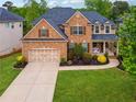 Traditional brick home featuring a manicured lawn, inviting front porch, and two-car garage at 280 Lakestone Pkwy, Woodstock, GA 30188