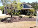 Charming two-story home boasts mature landscaping, inviting front porch and manicured lawn at 4960 Shade Creek Xing, Cumming, GA 30028