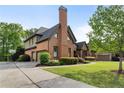 Side view of a red brick home featuring an attached three-car garage, driveway, landscaped yard, and mature trees at 1062 Meadow Grass Ln, Powder Springs, GA 30127