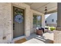 Inviting front porch with brick columns, seating area, and a decorative wreath on the front door at 500 S Hill St, Buford, GA 30518