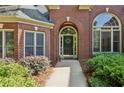 Close-up of a brick home's front door with an arched entrance and detailed landscaping at 378 Rhodes House Dr, Suwanee, GA 30024