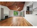 Sun-drenched living room with wood floors, fireplace, skylight, and an opening to the kitchen area with natural views at 3863 Dundee Ne Dr, Roswell, GA 30075