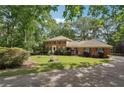 Beautiful brick home nestled among trees with a green lawn and charming curb appeal and long driveway at 5027 Castlewood Sw Dr, Lilburn, GA 30047