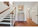 Hallway with wood floors, stairs, white trim, artwork and open doorways into other rooms at 5027 Castlewood Sw Dr, Lilburn, GA 30047