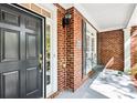 Inviting covered front porch features a brick facade and a black front door with sidelight and a place to sit at 8640 Amsbury Way, Cumming, GA 30041