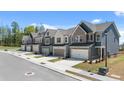 Exterior elevation of townhomes with two-car garages and professionally landscaped front yards on a sunny day at 2815 Habibi Ct, Buford, GA 30519