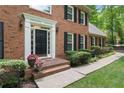 Close-up of a beautiful brick home's entrance with a stylish black door and decorative plants at 1440 Sandford Sw Trl, Lilburn, GA 30047
