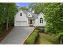 Charming white brick home featuring a two-car garage, and lush green landscaping at 7830 Kings Point Dr, Cumming, GA 30041