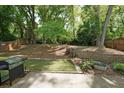 Secluded backyard featuring mature trees, a retaining wall, and a stainless steel grill on concrete patio at 2980 Porsche Nw Pl, Kennesaw, GA 30144