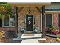 Stone front porch featuring a welcoming front door adorned with flowers and flanked by potted plants at 5950 Hidden Ridge Ct, Cumming, GA 30028