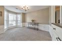 Bright living room with a bay window, chandelier, and elegant white wainscoting at 1703 Bentridge Nw Dr, Kennesaw, GA 30144