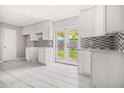 Well-lit kitchen featuring white cabinets and mosaic backsplash, with backyard access at 2529 Ryne St, Atlanta, GA 30318