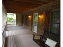 The covered front porch featuring brick walls, a wooden ceiling, and a porch swing at 553 Old Mill Ct, Norcross, GA 30093