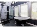 Bathroom featuring a modern shower and a freestanding tub with claw feet, complemented by ample natural light at 225 Nacoochee Dr, Woodstock, GA 30188