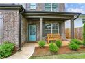 Inviting front porch featuring brick accents, a bench, and a welcoming teal front door at 461 Silver St, Buford, GA 30518
