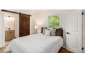 Cozy bedroom with natural light, a barn door to the bathroom, and hardwood floors at 3181 Pennington Sw Cir, Atlanta, GA 30354