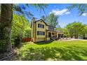 Charming yellow two-story home with black shutters and a lush green lawn, surrounded by mature trees at 664 Somerset Dr, Lawrenceville, GA 30046