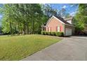 Side view of brick home featuring a long driveway and meticulously maintained lawn and landscaping at 4635 Rutledge Dr, Snellville, GA 30039
