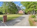 Brick home with a lengthy driveway, manicured lawn, and framed by mature trees at 4635 Rutledge Dr, Snellville, GA 30039
