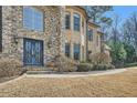 Elegant stone facade featuring a decorative front door, manicured landscaping, and a well-maintained lawn at 2015 Shaudi Ln, Atlanta, GA 30345