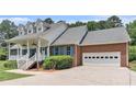 Brick home featuring an attached two-car garage and a covered front porch with white railing and blue shutters at 2949 Lake Spivey Pkwy, Jonesboro, GA 30236