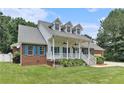 Inviting brick home featuring a classic front porch, white railings, dormer windows, and a well-maintained lawn at 2949 Lake Spivey Pkwy, Jonesboro, GA 30236