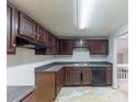 This kitchen features dark wood cabinets, countertops, double sink, and black dishwasher at 1060 S Millard Way, Stone Mountain, GA 30088