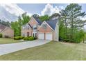Exterior shot of a brick home with a long driveway, a two car garage, and lush green lawn at 4290 Grand Teton Pkwy, Suwanee, GA 30024