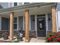 Close-up of the front porch featuring wood pillars, a decorative statue, and vibrant red flowers at 162 Greenbrier Way, Canton, GA 30114
