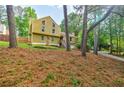 View of a two-story house with yellow siding and stone accents, surrounded by lush greenery and trees at 5105 Davidson Ne Rd, Marietta, GA 30068