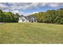 Expansive lawn surrounds this modern farmhouse, creating a picturesque setting with mature trees on the horizon at 613 Nebo Rd, Dallas, GA 30157