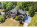 An aerial view showcases this property's brick architecture, in-ground pool and surrounding mature trees at 225 Farmbrooke Ct, Sandy Springs, GA 30350
