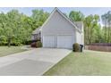 Side view of a lovely home featuring a two-car garage and a long driveway lined with green grass at 1625 Brisbane Dr, Dacula, GA 30019