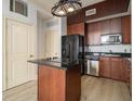 Compact kitchen with black appliances, dark wood cabinets, and an island with black countertop at 57 Forsyth Nw St # 12E, Atlanta, GA 30303