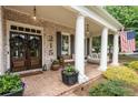 Inviting front porch featuring brick flooring, columns, comfortable seating, and stylish accents at 215 Scott Xing, Roswell, GA 30076