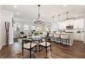 Open-concept living room featuring wood floors, modern lighting, and a spacious seating area and kitchen island at 3747 Silvery Way, Powder Springs, GA 30127