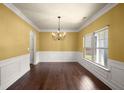 Elegant dining room featuring hardwood floors, wainscoting, and a chandelier, perfect for formal entertaining at 3940 Village Estates Ct, Cumming, GA 30040