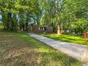 Single-story brick home with concrete driveway, set amidst a lush, green lawn and mature trees at 233 Banberry Se Dr, Atlanta, GA 30315