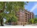 A brick apartment building featuring multiple balconies and lush, green trees surrounding the property at 77 Peachtree Ne Pl # 107, Atlanta, GA 30309
