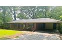 Ranch-style brick home featuring a covered carport and a lush, tree-filled front yard at 6470 Sherwood Trl, Austell, GA 30168